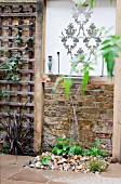 THE DRAWING ROOM GARDEN  URBAN LONDON GARDEN  WATER FEATURE AND CHAIR WITH FILIGREE PATTERN WALL PLAQUE  DESIGNED BY: EARTH DESIGNS.