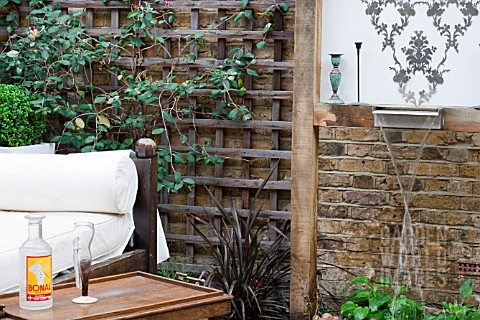 THE_DRAWING_ROOM_GARDEN__URBAN_LONDON_GARDEN__WATER_FEATURE_AND_CHAIR_WITH_FILIGREE_PATTERN_WALL_PLA