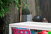 THE DRAWING ROOM GARDEN  URBAN LONDON GARDEN  TABLE AND CHAIRS  CHAIN SCREEN DIVIDING SHED AND BARBECUE AREA.  DESIGNED BY: EARTH DESIGNS.