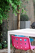 THE DRAWING ROOM GARDEN  URBAN LONDON GARDEN  DETAIL OF PINK CHAIR WITH CHAIN SCREEN AND JASMINUM  DESIGNED BY: EARTH DESIGNS.