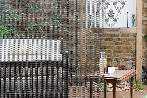 THE_DRAWING_ROOM_GARDEN__URBAN_LONDON_GARDEN__SEATING_AREA_AROUND_WATER_FEATURE_THRIUGH_CHAIN_SCREEN
