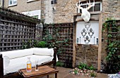 THE DRAWING ROOM GARDEN  URBAN LONDON GARDEN  THE SEATING AREA  WITH THE ILLUMINATED MOOSE HEAD TROPHY AND THE WATER FEATURE  DESIGNED BY: EARTH DESIGNS.