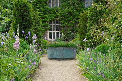 LARGE_COPPER_PLANTER_AND_BORDERS_WITH_IRIS_AND_ERYSIMUM_AT_HANHAM_COURT