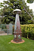 OBELISK WITH BROLLY AT THE GARDEN OF SURPRISES, BURGHLEY HOUSE, STAMFORD, DESIGNER GEORGE CARTER.