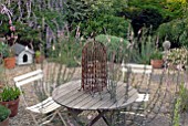 TABLE AND CHAIRS ON PATIO WITH SELF-SEEDED LINARIA PURPUREA CANON WENT