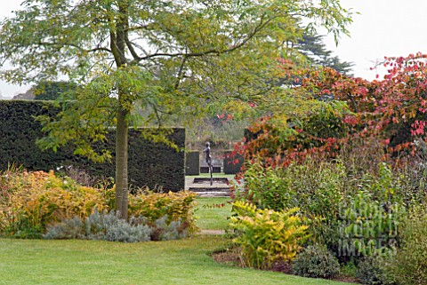 AUTUMNAL_VIEW_THROUGH_YEW_HEDGE_OF_STATUE_AND_LILY_PONDS_AT_OZLEWORTH_PARK_GLOUCESTERSHIRE