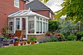 SUBURBAN BACK GARDEN WITH CONSERVATORY, BORDERS AND LAWN