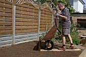 MAN ADDING TOPSOIL FROM WHEELBARROW