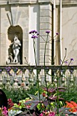 VERBENA BONARIENSIS AND RICINUS FOLIAGE IN FRONT OF STATUE IN NICHE AT DYFFRYN GARDENS,  WALES