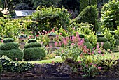 VIEW OF TOPIARY FROM ACROSS THE MILL POND AT MILL DENE GARDEN,  BLOCKLEY,  GLOUCESTERSHIRE,  JUNE