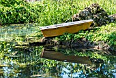 REFLECTION OF A BOAT AND GRASSES ON A BOATING LAKE