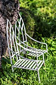 IRON GARDEN CHAIRS RESTING AGAINST A FALLEN TREE TRUNK