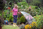 WOMAN WATERING FLOWERS IN GARDEN BED