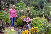 WOMAN WATERING FLOWERS IN GARDEN BED