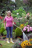 WOMAN WATERING FLOWERS IN GARDEN BED