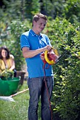 PERSON CUTTING PRUNING HEDGES WITH ELECTRIC TRIMMER