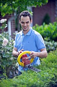 PERSON CUTTING PRUNING HEDGES WITH ELECTRIC TRIMMER