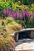 CURVED WOODEN BENCH IN THE HERBACEOUS BORDER AT RHS HARLOW CARR