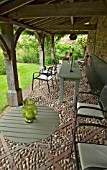 TABLES AND CHAIRS UNDER THE LOGGIA WITH OAK ARCHES AND COBBLED FLOOR AT WOLLERTON OLD HALL