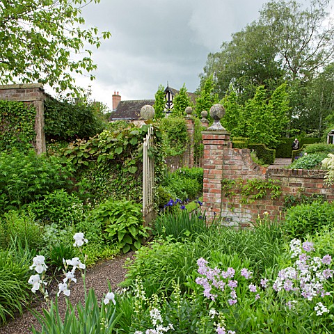 PATH_THROUGH_WROUGHT_IRON_GATEWAY_WITH_BORDERS_OF_HERBACEOUS_PERENNIALS_AT_WOLLERTON_OLD_HALL