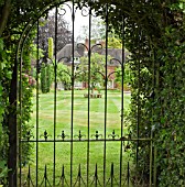 LOOKING AT GARDEN AND HOUSE THROUGH WROUGHT IRON GATE AT YARLET HOUSE STAFFORDSHIRE