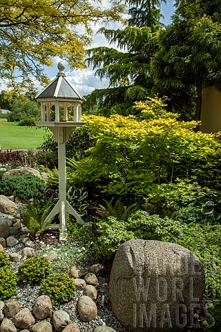 Model_dovecote_on_gravel_area_large_stone_mature_trees_and_shrubs_in_June_Early_Summer_Ashwood_NGS_W