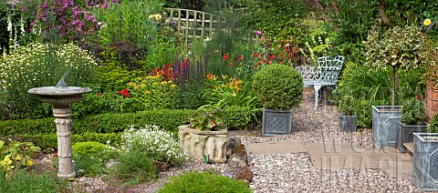A_plant_lovers_cottage_garden_borders_of_herbaceous_perennials_grey_metal_containers_with_shaped_box