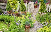 Path down garden runs through gate flanked with two Ulmus Wredei and Alchemilla Mollis Lady`s Mantle