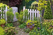 Open pale fence with Euphorbia and containers around gate