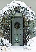 Snow covered front garden and porch with clematis trailing around the front door in winter