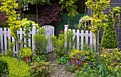 Open pale fence with Euphorbia and containers around gate