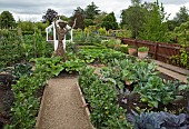 Kitchen garden with salad crops and leafy vegetables, willow figure and greenhouse