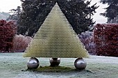 Plastic pyramidical sitting on large metal spheres balls, a sculpture in winter