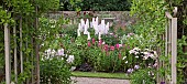 Gateway looking out onto border of of colour combination of light to dark pinks herbaceous perennials