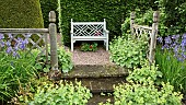 Terraced seating area, with Alchemilla mollis ladys mantle with blue Iris against oak fencing