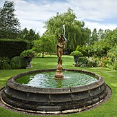 Rectangular water fountain with statue of boy in centre of lawn