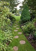 Long borders with mixed summer perennials mature shrubs and trees