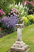 Wide borders of herbaceous perennials ornate sun-dial