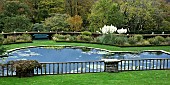 Ornate garden pond backed by Yew hedge on terraced garden in late autumn November