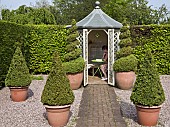 Summerhouse twisted and pyramid box in terracotta pots on grave, brick pathway