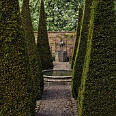 Carved limestone wellhead,four quadrant beds are separated by tall thin yew spires in a cruciform.