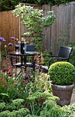 A SMALL PATIO TABLE AND CHAIRS WITH PLANTS IN POTS