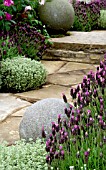 LAVANDULA STOECHAS AGAINST PAVED PATH WITH DECORATIVE STONE BALLS