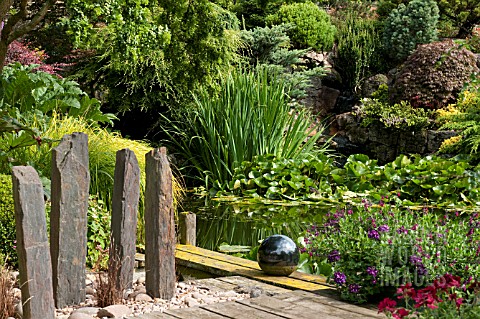 JOHNS_GARDEN_AT_ASHWOOD_NURSERIES___POOL_WITH_SURROUNDING_SHRUBS_CONIFERS_TREE_AND_STAGING