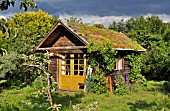 GARDEN HOUSE WITH GREEN ROOF IN A NATURAL GARDEN