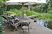 WOODEN DECKING AREA WITH SEATS AT A SWIMMING POND