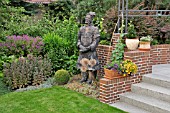 PERENNIAL BORDER WITH POTTED PLANTS AND REPRODUCTION OF A CHINESE CLAY WARRIOR