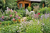 WOODEN HOUSE IN A RICH FLOWERING GARDEN. DESIGN: MARIANNE AND DETLEF LUEDKE