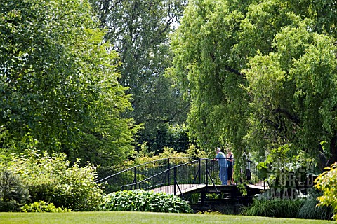 VISITORS_STANDING_ON_THE_BRIDGE_OVER_THE_LOWER_POND_AT_RHS_GARDEN_HYDE_HALL__IN_JUNE