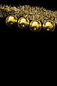 FOUR YELLOW CHRISTMAS BALLS HANGING AGAINST A BLACK BACKGROUND